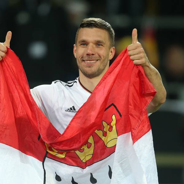 ukas Podolski verabschiedet sich nach dem Spiel von den Fans und hält dabei eine Kölner Fahne.