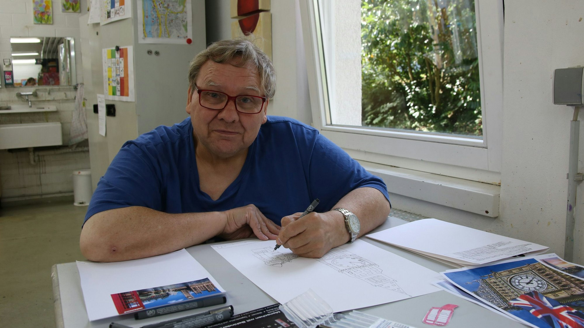 Ein Mann an einem Tisch, einen Stift in der Hand und ein Blatt Papier vor sich.