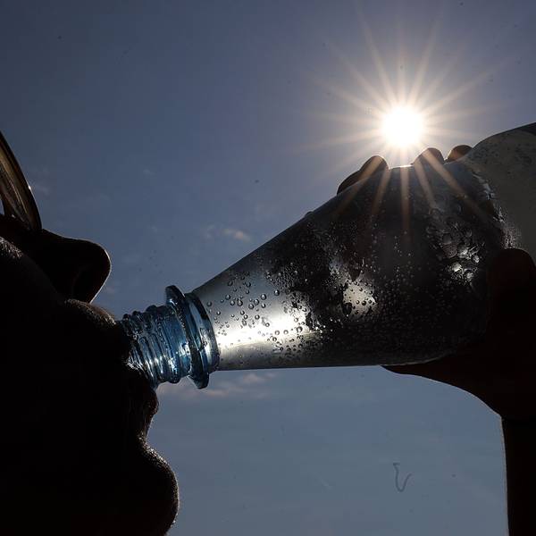 Eine Frau trinkt in der Sonne Mineralwasser.