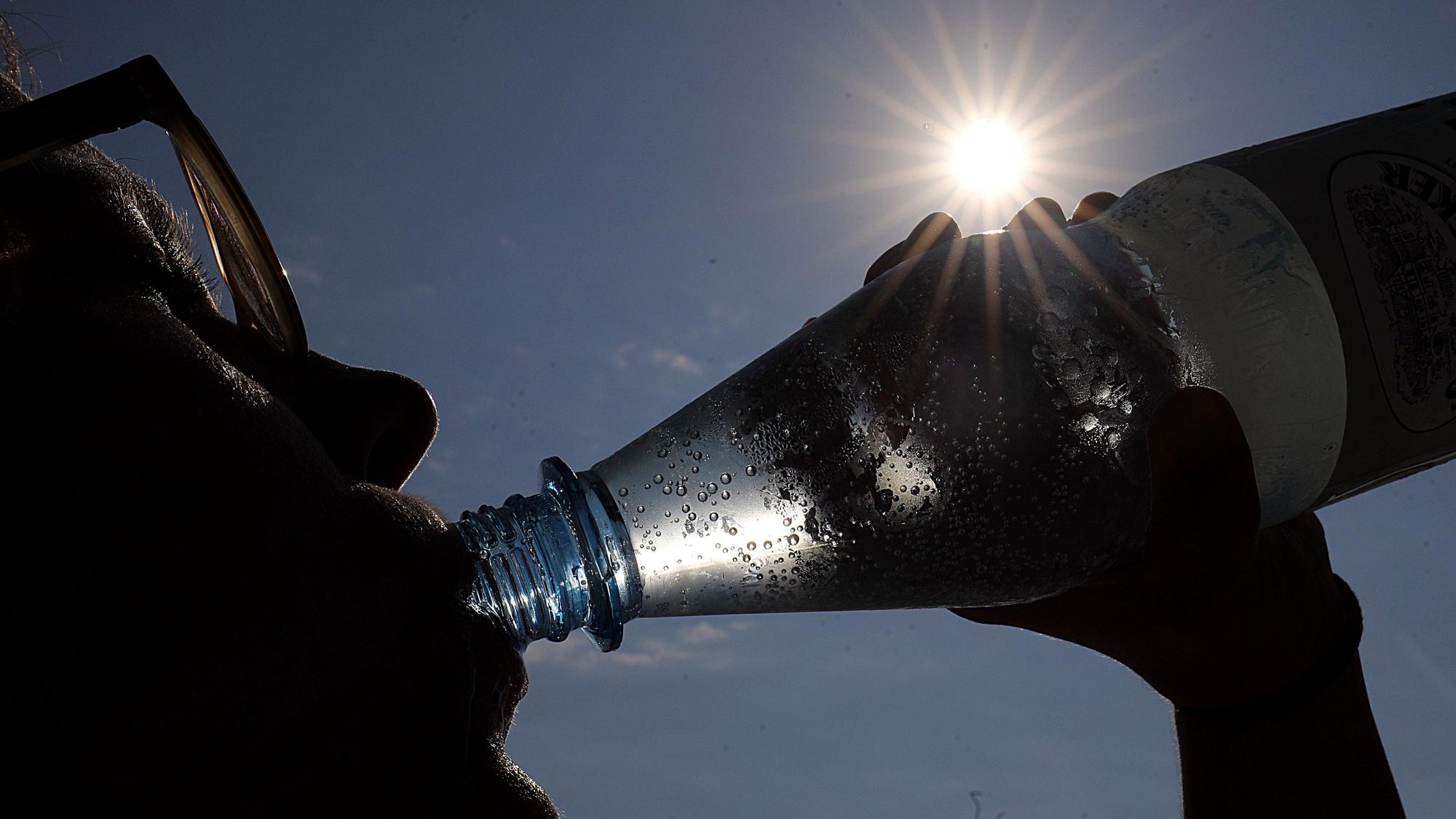 Eine Frau trinkt in der Sonne Mineralwasser.