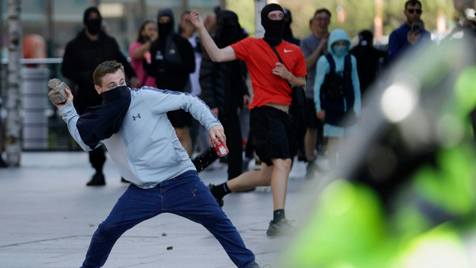 Ein Randalierer wirft in Liverpool einen Stein in Richtung von Polizeikräften.