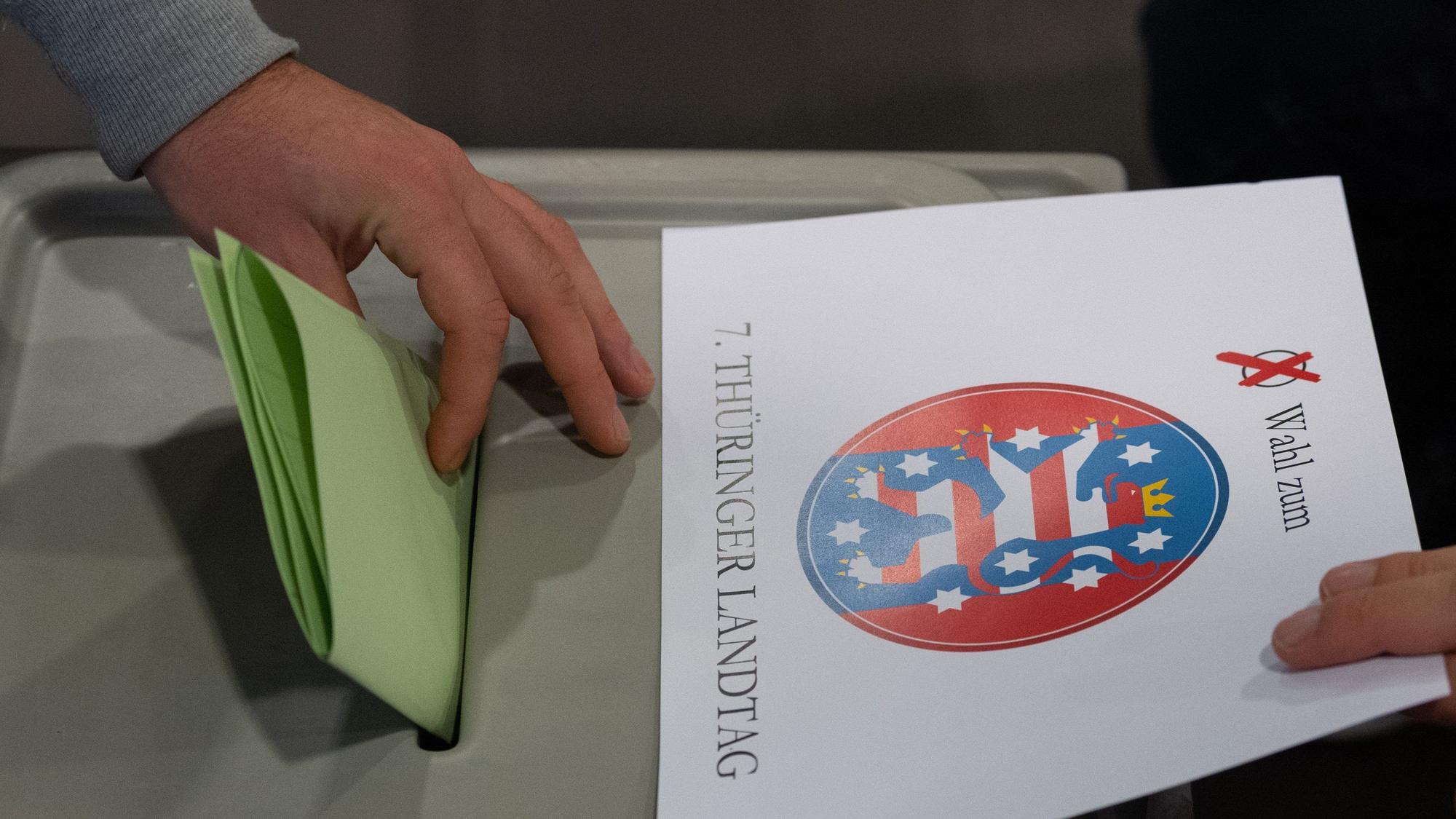 Ein Wähler wirft bei der Stimmabgabe zur Landtagswahl in Thüringen seinen Wahlzettel in einem Wahllokal in eine Wahlurne.