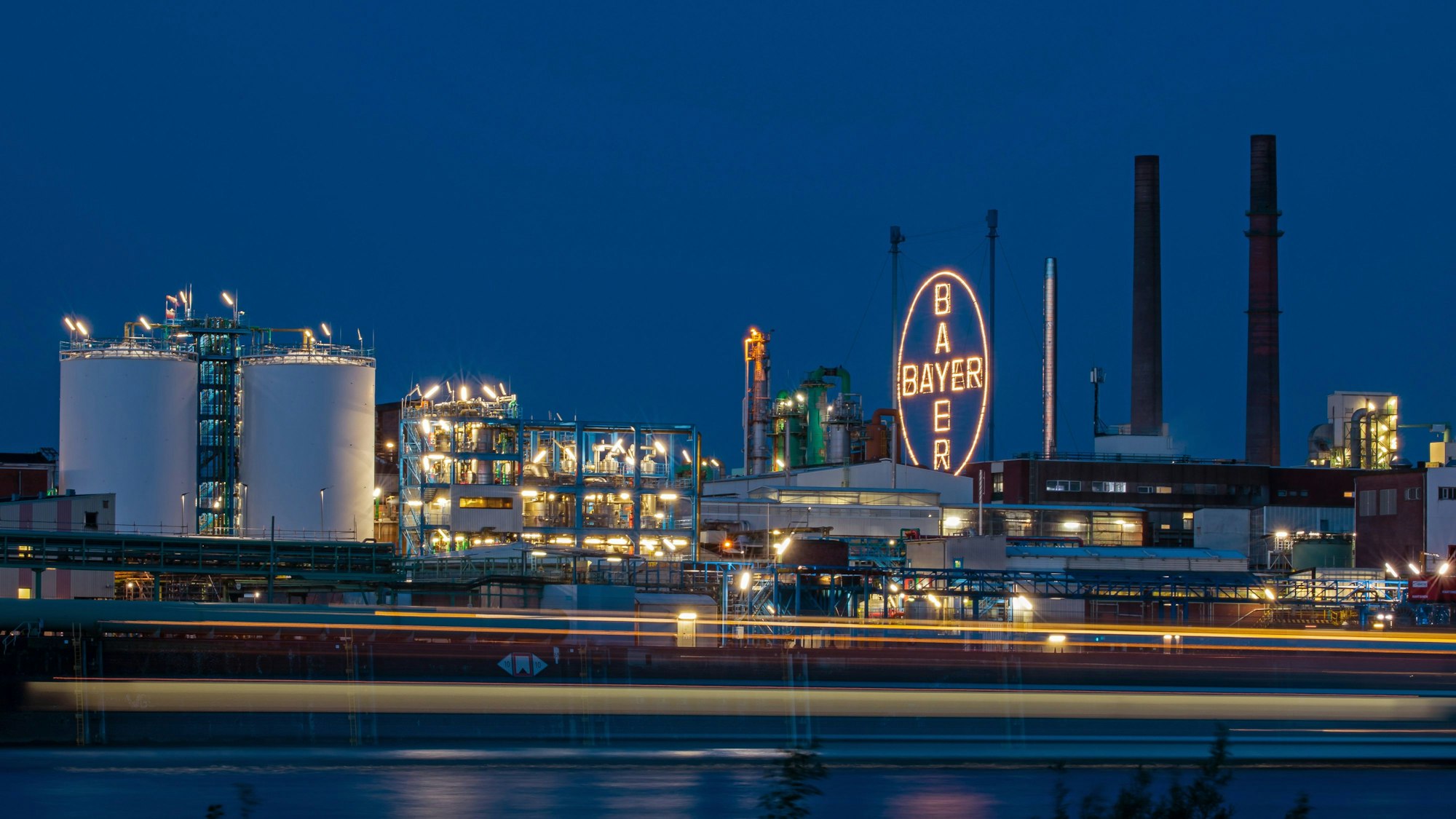 ARCHIV - 14.05.2019, Nordrhein-Westfalen, Köln: Das Bayer Kreuz, das Logo des Unternehmens, leuchtet auf dem Werksgelände von Bayer in Leverkusen, gegenüber dem Rheinufer in Köln. (zu dpa: «Bayer hat seit Jahresbeginn 3200 Stellen abgebaut») Foto: Oliver Berg/dpa +++ dpa-Bildfunk +++