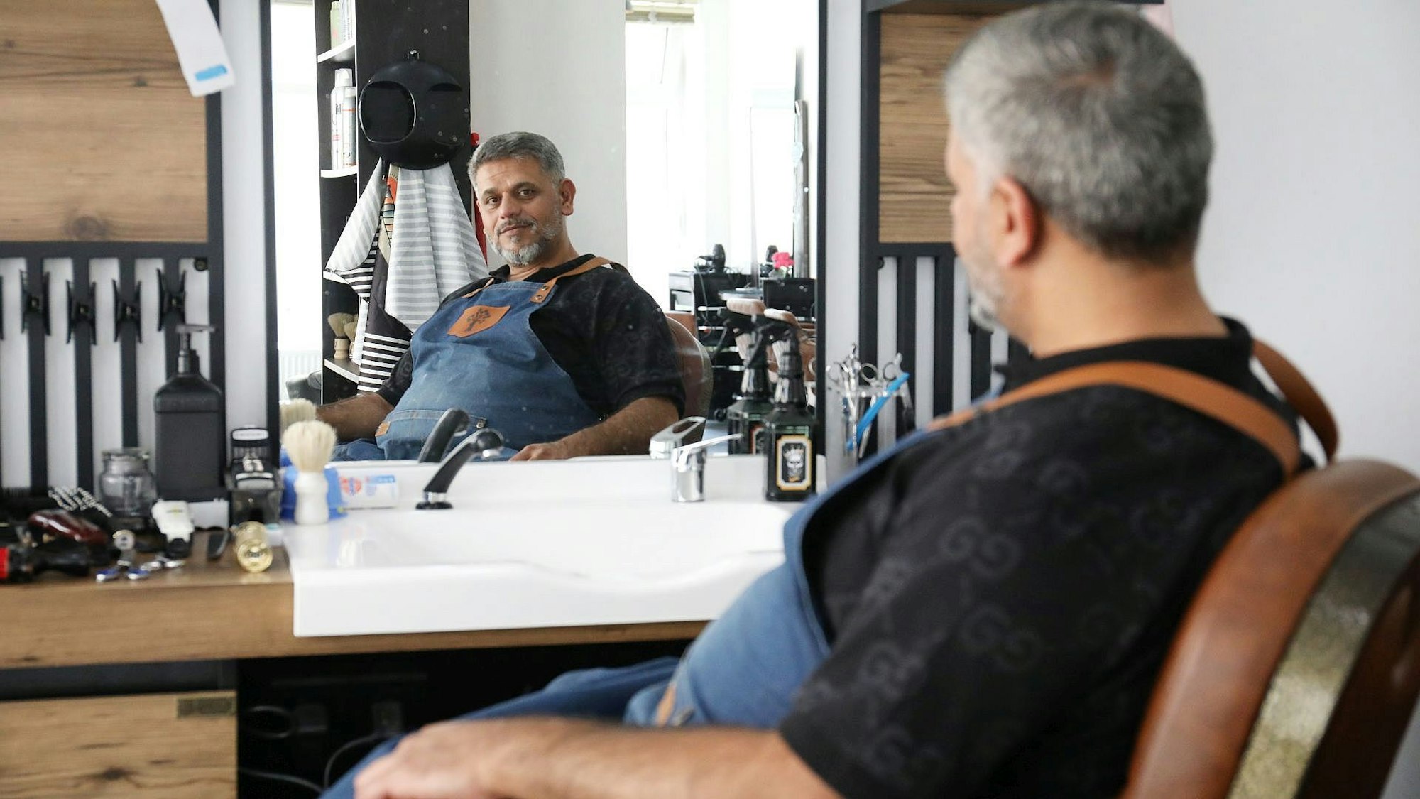 Ein Mann sitzt in einem Friseursalon vor dem Spiegel