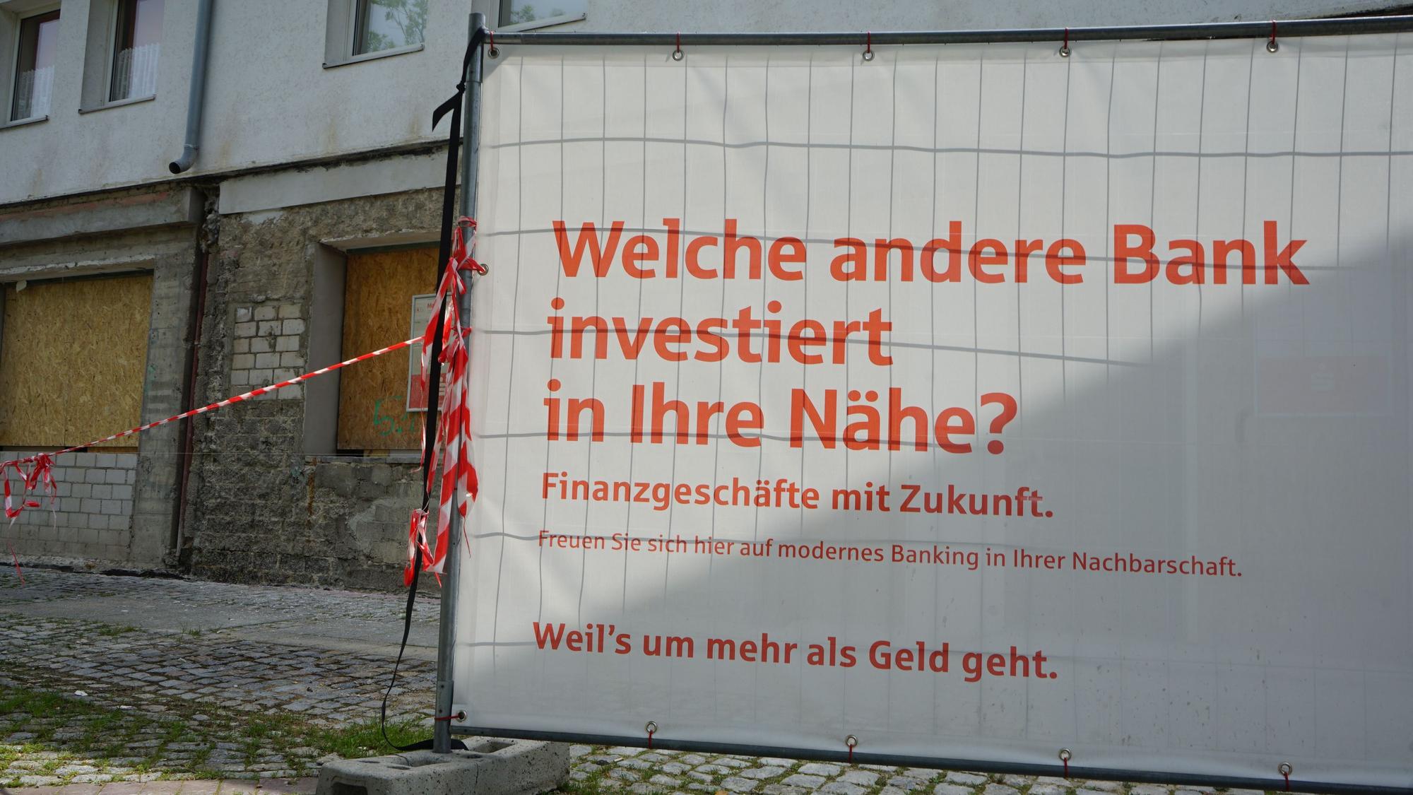 Das Foto zeigt einen Bauzaun vor einer Bauruine.