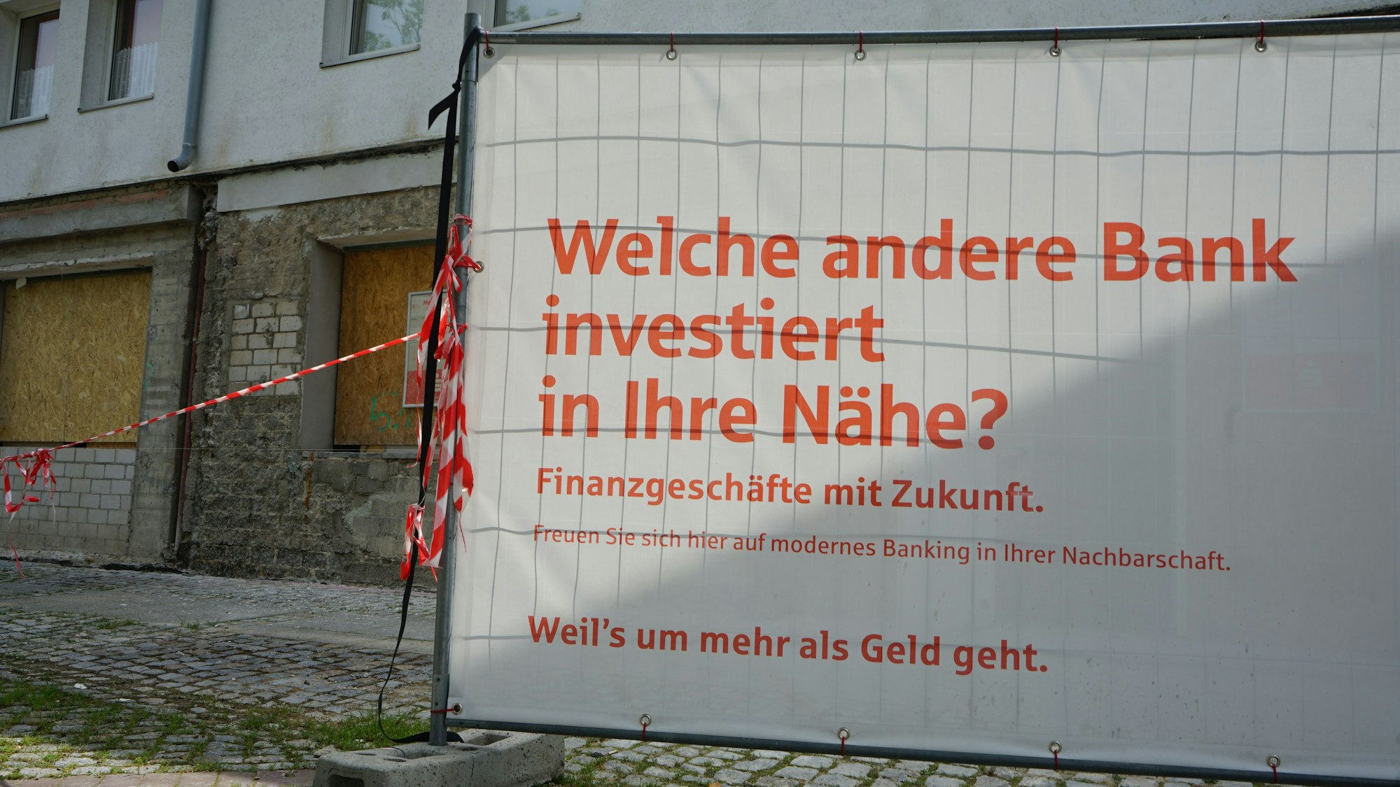 Das Foto zeigt einen Bauzaun vor einer Bauruine.