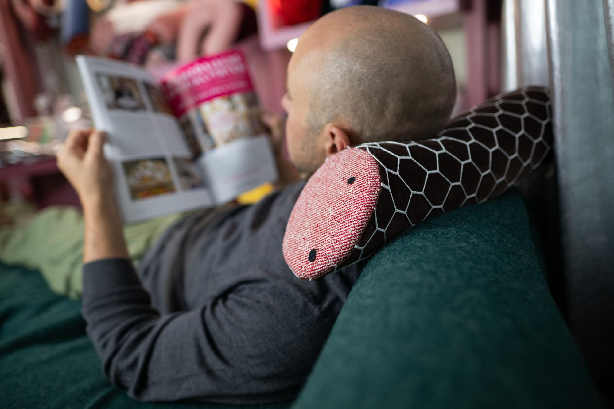 Ein Mann liegt auf einem Kissen in Form einer Salami des Labels Aufschnitt Berlin der Designerin Silvia Wald.