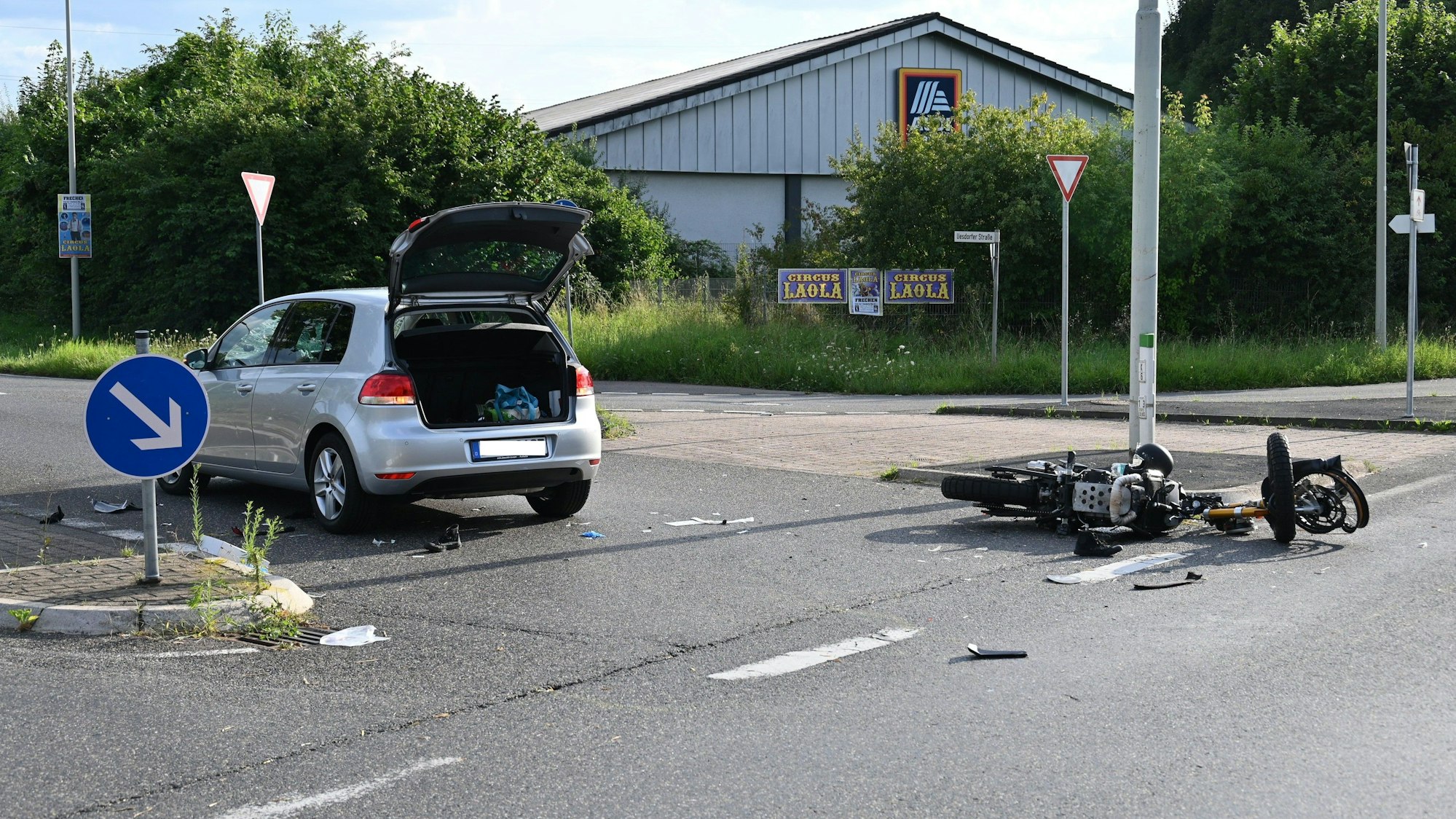Ein zerstörtes Motorrad liegt neben einem Auto auf der Straße.