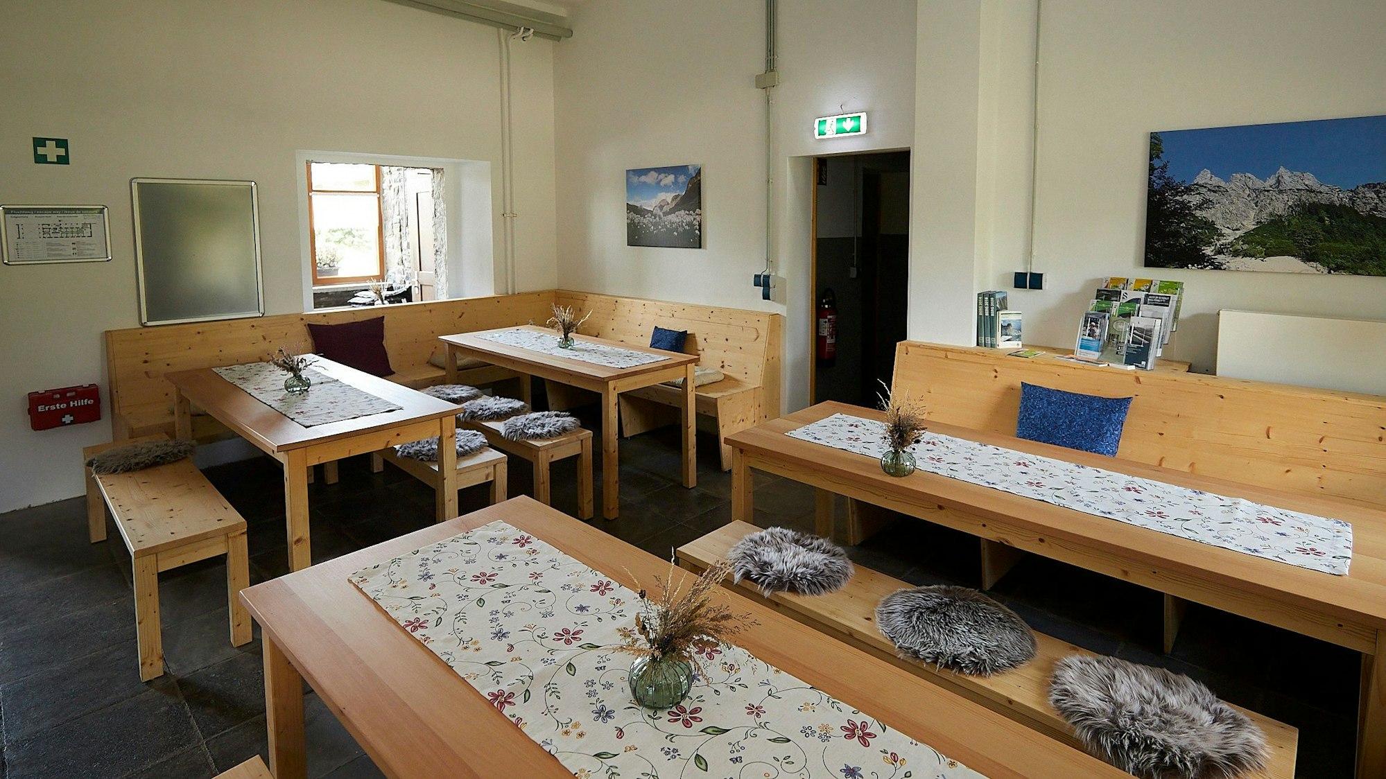 Mehrere Tische und Bänke aus Holz stehen in einem großen Raum in der Hütte des Alpenvereins in Vogelsang.