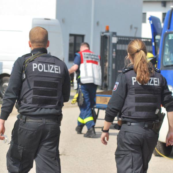 Zwei Polizisten und ein THW-Helfer gehen am 27. April 2022 auf ein Gebäude zu. Darin wird eine Cannabis-Plantage sichergestellt.