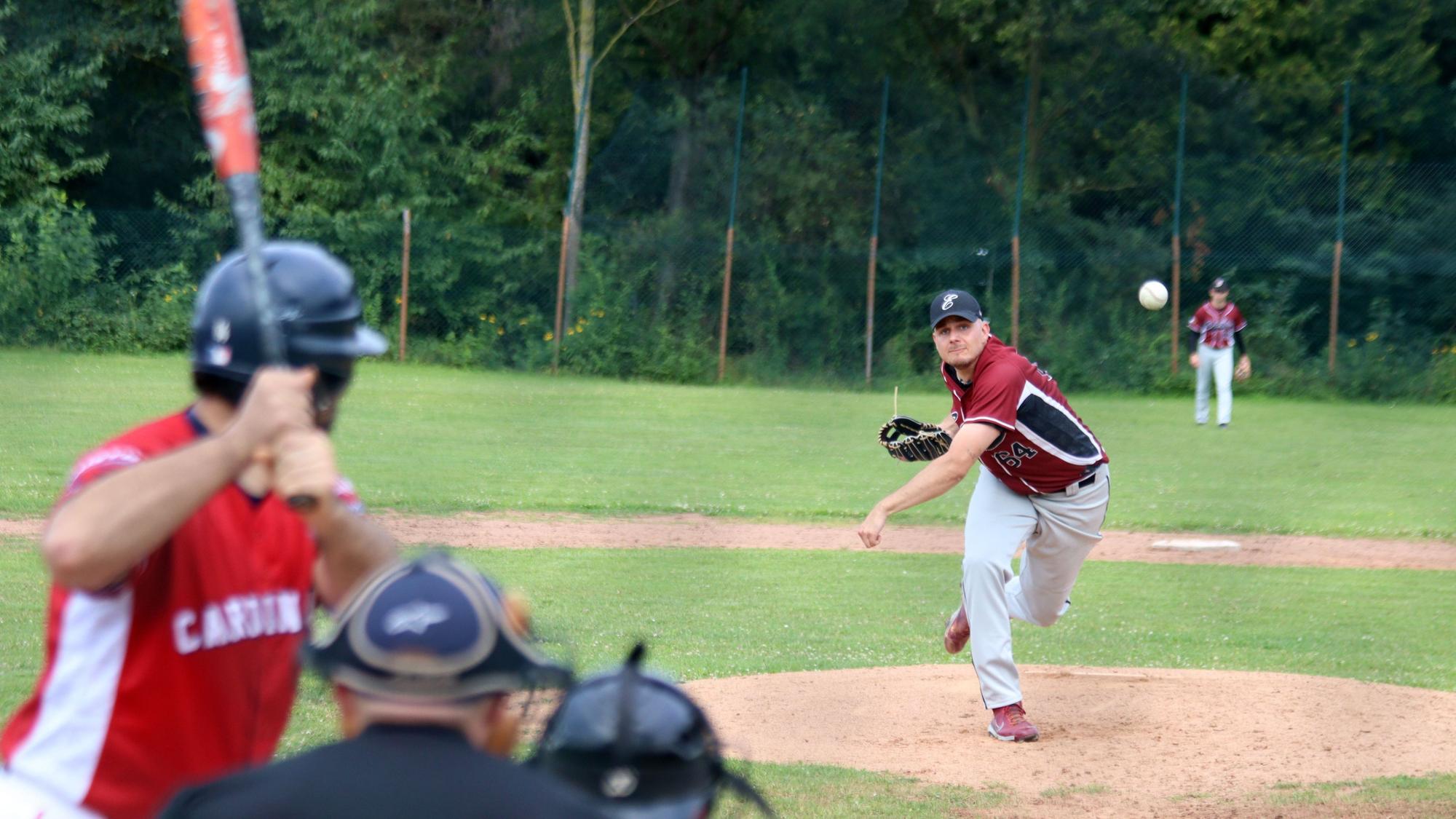 Ein Baseballspieler wirft einen Ball, ein weiterer Spieler steht bereit, den Ball zu schlagen.