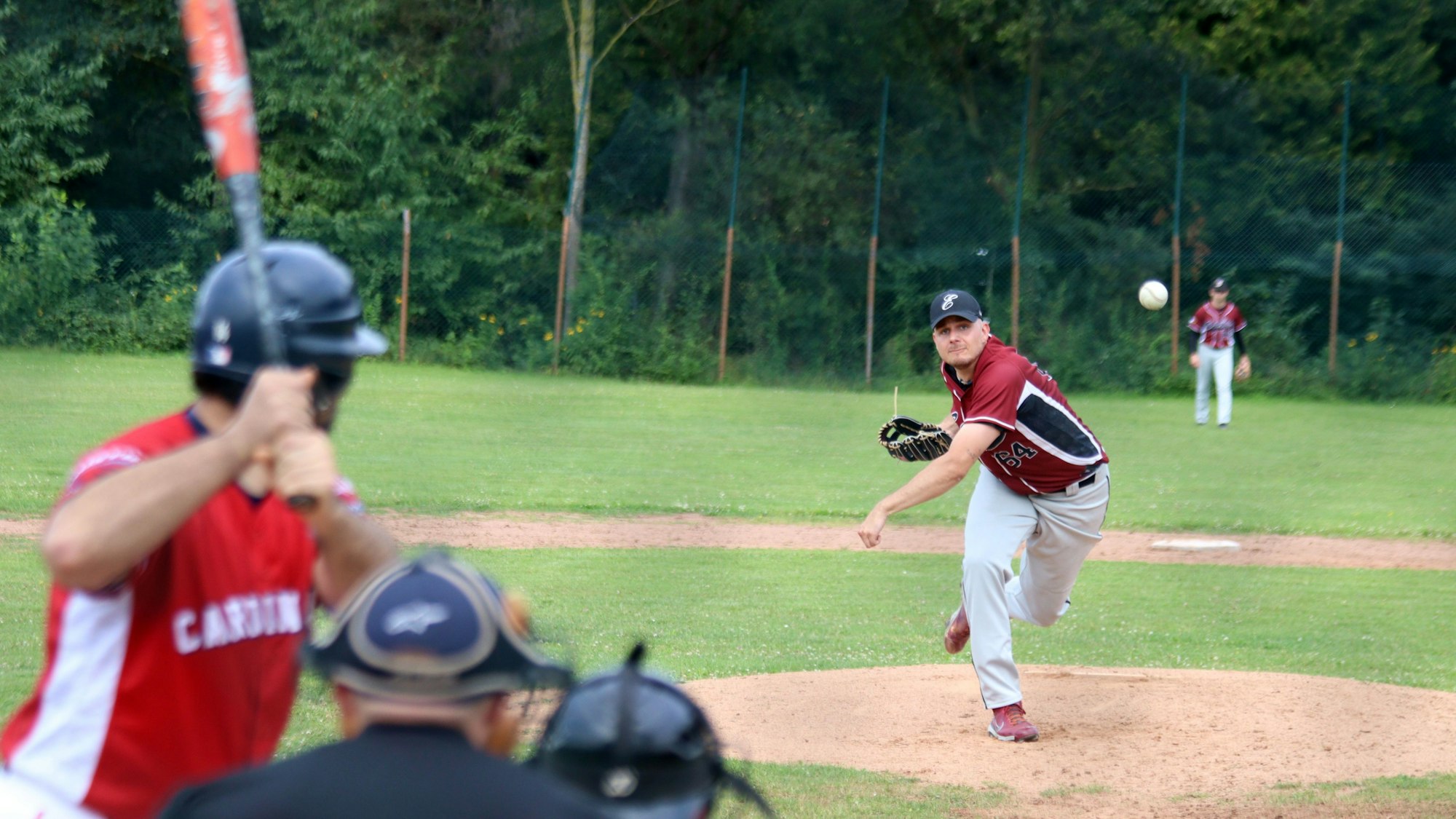 Ein Baseballspieler wirft einen Ball, ein weiterer Spieler steht bereit, den Ball zu schlagen.