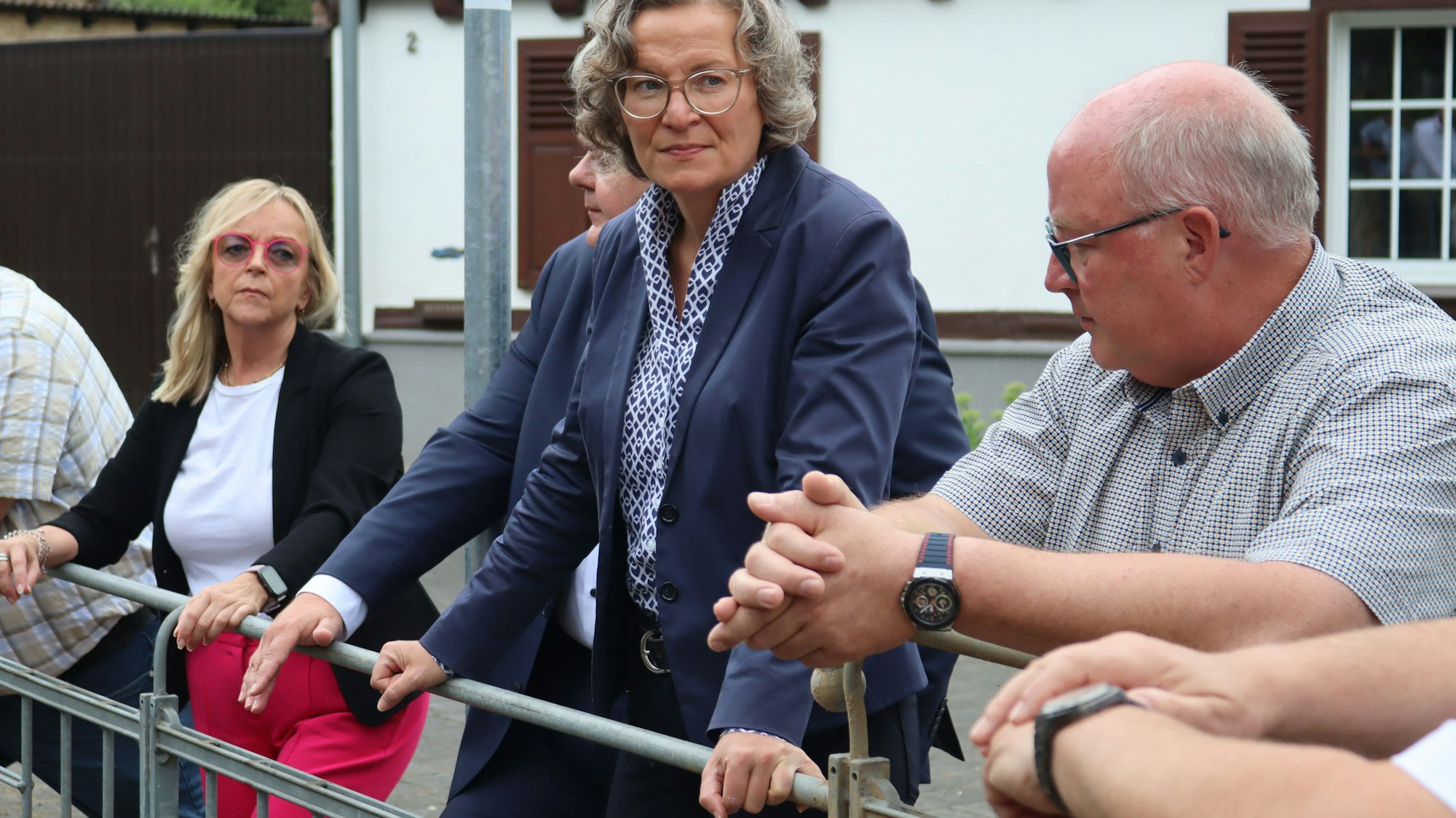 Ministerin Ina Scharrenbach lehnt sich an ein Geländer und schaut sich den Durchlass des Dreisbaches an.