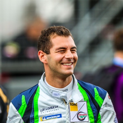 Rennfahrer Tobias Müller trägt seinen Rennoverall und lacht.