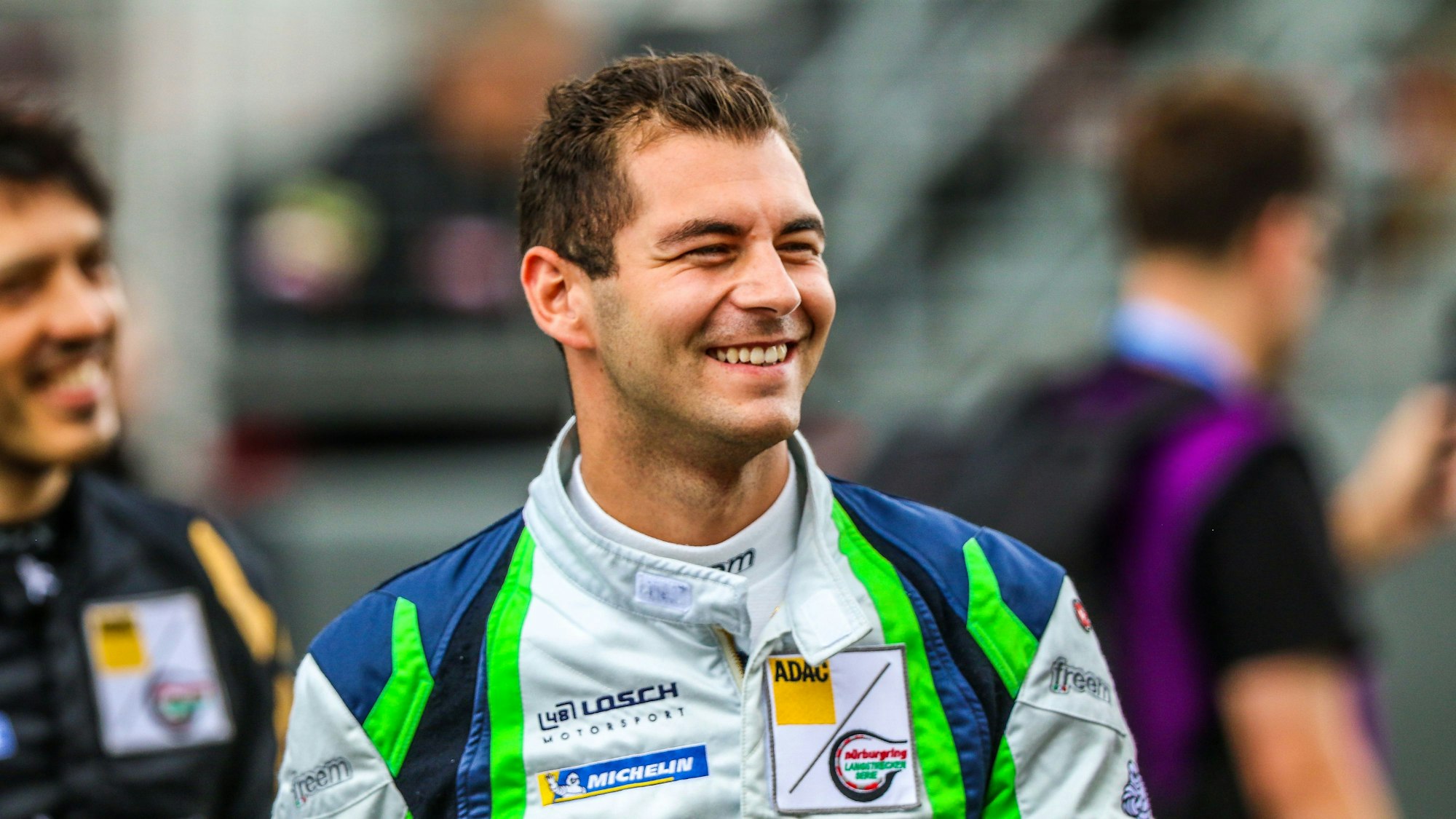 Tobias Müller, der einen Renn-Overall trägt, lacht.