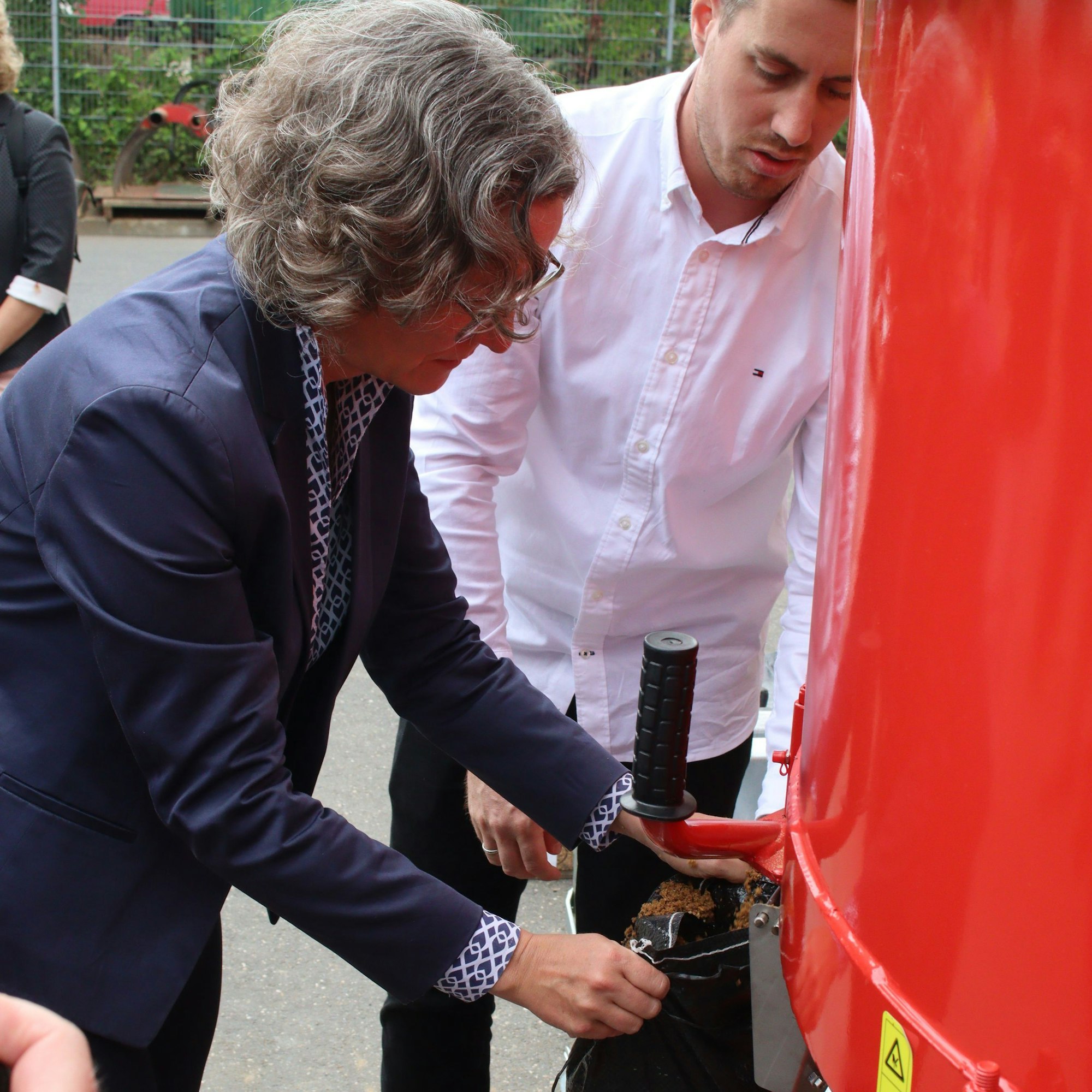 Ministerin Ina Scharrenbach hält einen Sack voll Sand in der Hand, den sie gerade befüllt hat.