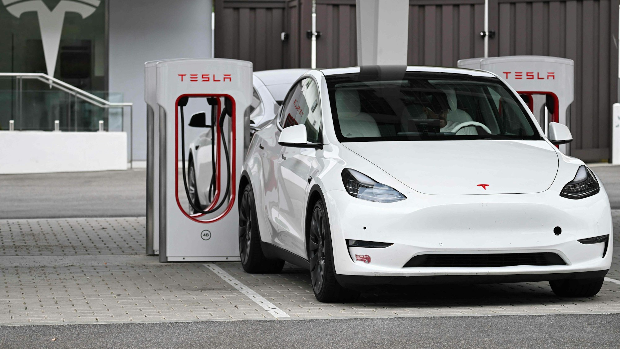 (FILES) A Tesla electric vehicle charges at a Tesla Supercharger location in Santa Monica, California on May 15, 2024. Tesla reported a hefty drop in second-quarter profits on July 23, 2024 due to the effect of price cuts while spending aggressively on artificial intelligence and other technology. Elon Musk's electric vehicle company reported profits of $1.5 billion, down 45 percent, on revenues of $25.5 billion, up two percent. (Photo by Patrick T. Fallon / AFP)