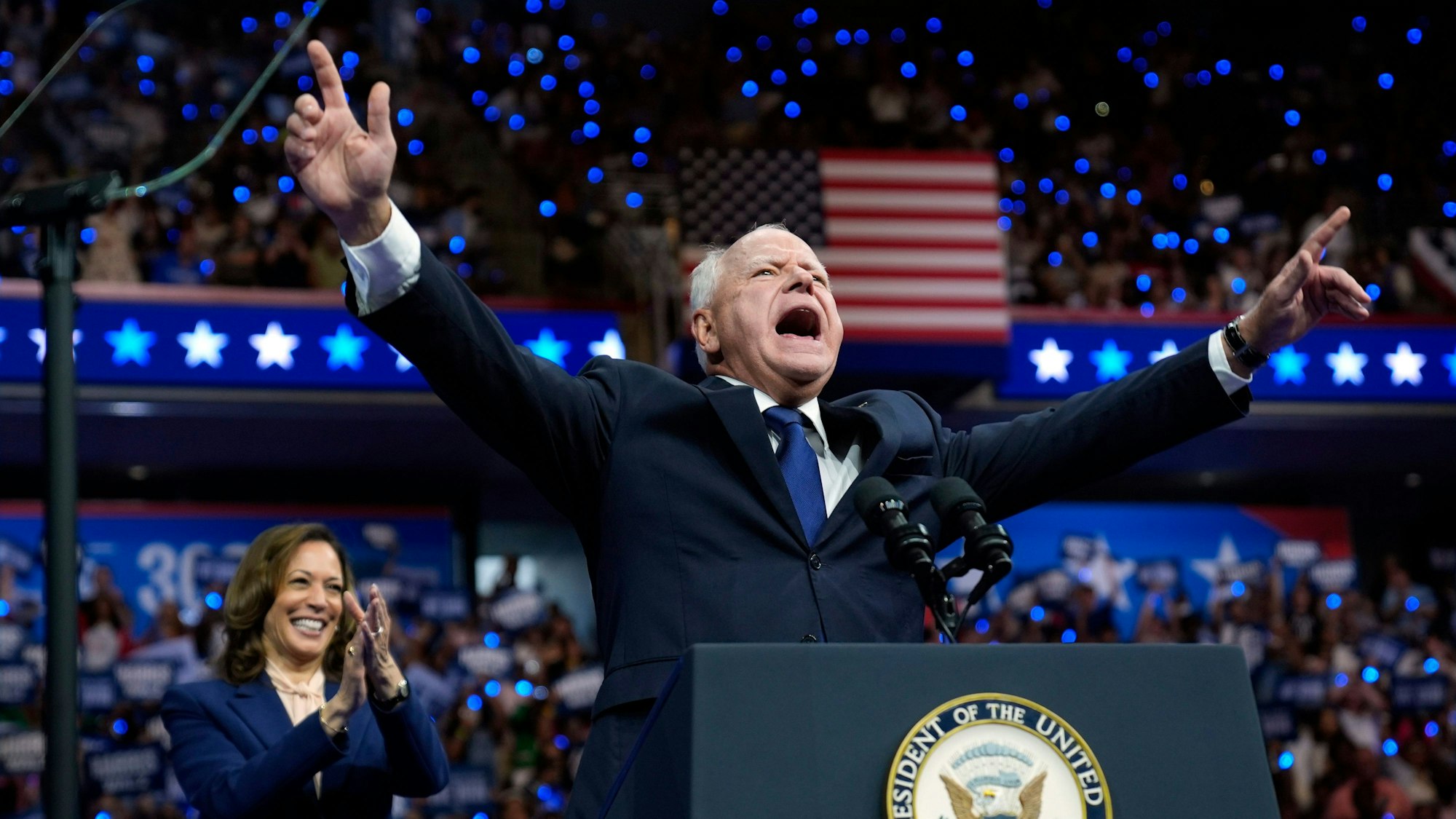 Tim Walz lässt sich von der Menge feiern. Kamala Harris applaudiert im Hintergrund.
