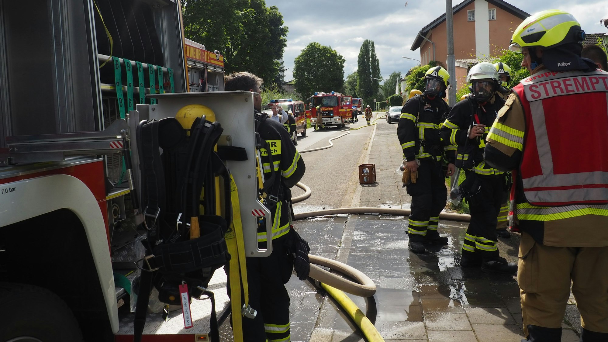 Feuerwehrleute und mehrere Feuerwehrfahrzeuge auf der Straße am Einsatzort in Antweiler.