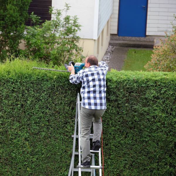 Ein Mann schneidet eine Hecke im Garten. (Symbolbild)