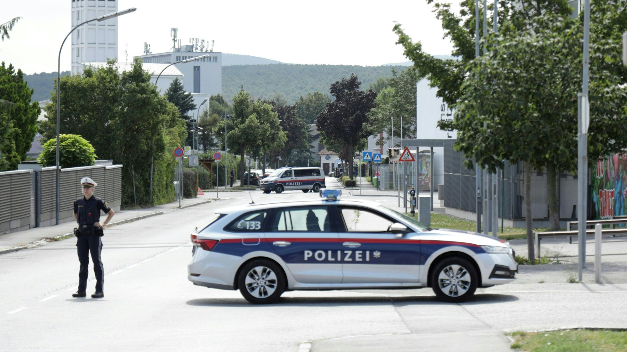 Ternitz: Ein Polizist und ein Polizeiwagen stehen am Einsatzort. In Österreich sind zwei Personen unter Terrorverdacht festgenommen worden. Sie hätten unter anderem Anschläge bei den bevorstehenden Konzerten von Taylor Swift in Wien geplant