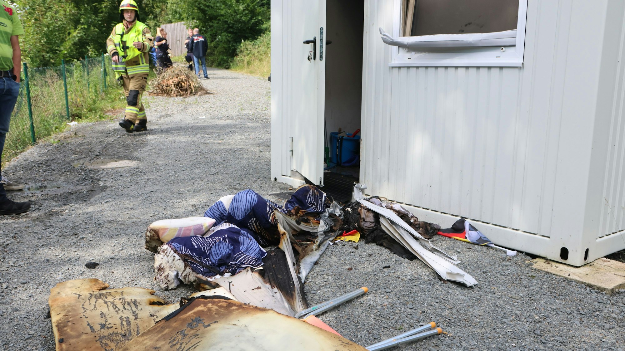 Verbrannte Materialien liegen vor einem Container.