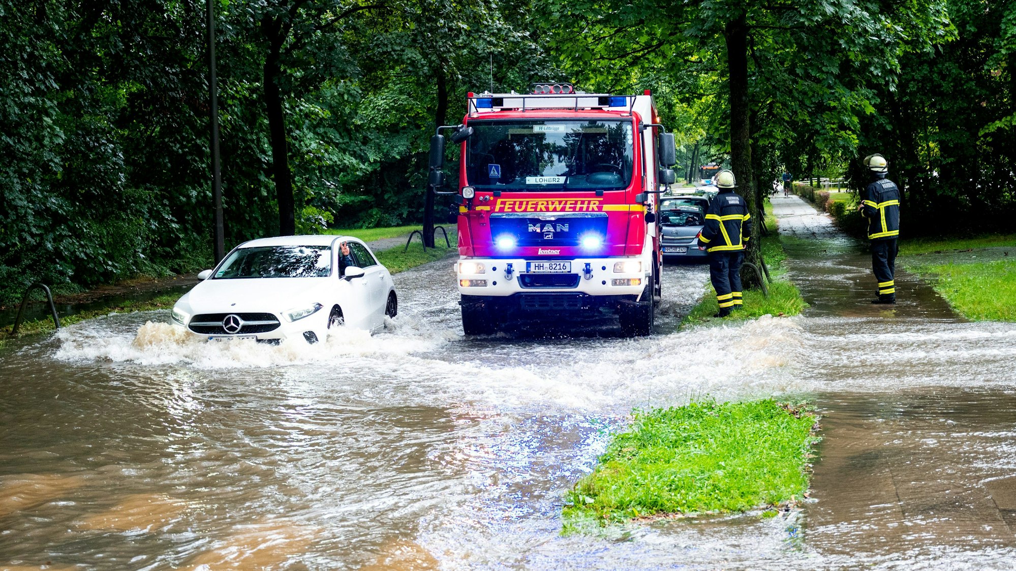 Hamburg: Ein Auto fährt im Stadtteil Lohbrügge durch eine überschwemmte Straße. Starkregen hat am Mittwoch (7. August) zu Überflutungen geführt.