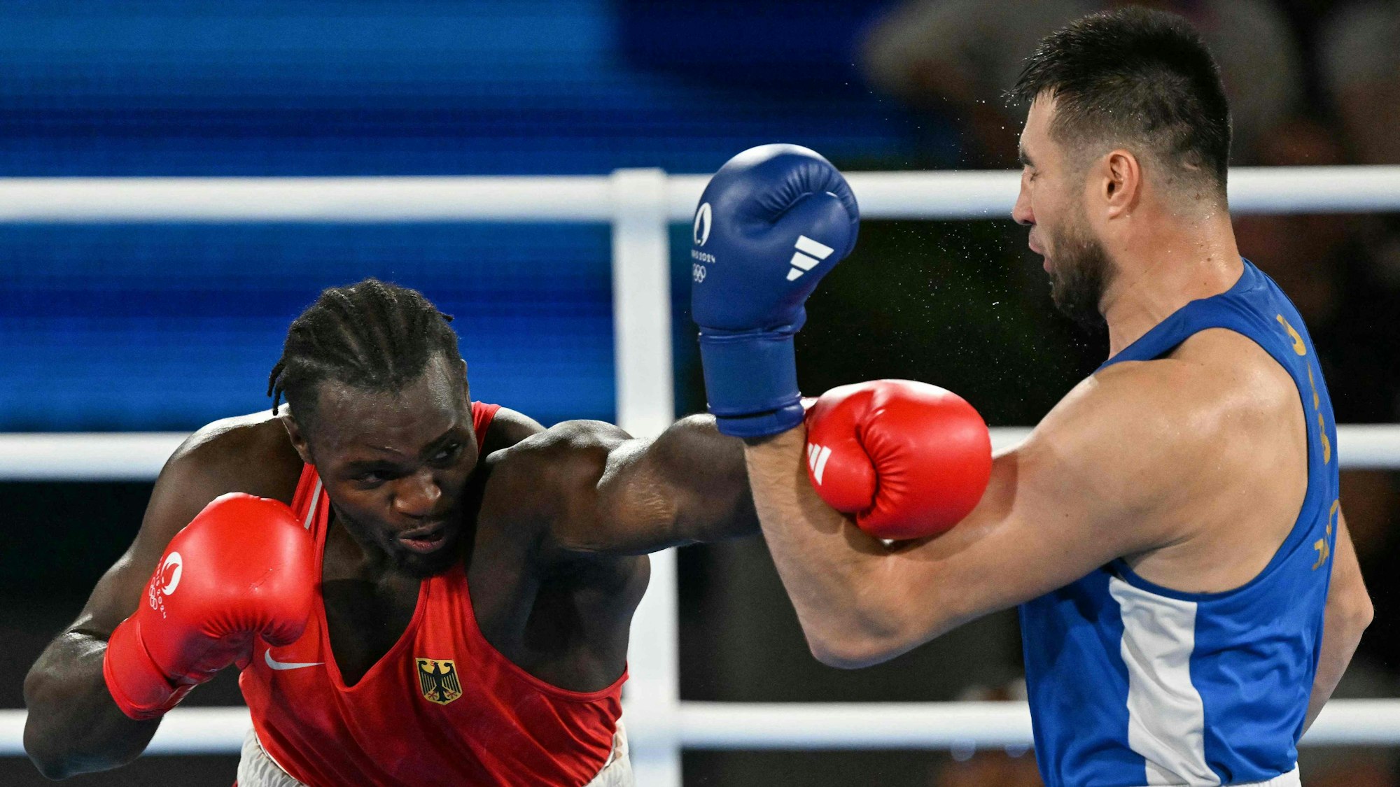 Germany's Nelvie Raman Tiafack and Uzbekistan's Bakhodir Jalolov (Blue) compete in the men's +92kg semi-final boxing match during the Paris 2024 Olympic Games at the Roland-Garros Stadium, in Paris on August 7, 2024. (Photo by MOHD RASFAN / AFP)