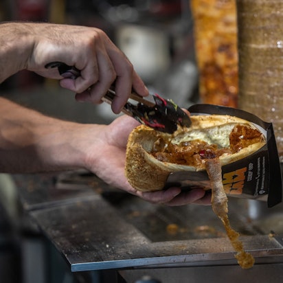 PRODUKTION - 07.08.2024, Baden-Württemberg, Heilbronn: Ein Mitarbeiter einer Dönerbude legt Fleisch in einen Döner. (zu dpa: «Obergrenze für Dönerbuden? Das steckt hinter der CDU-Idee») Foto: Christoph Schmidt/dpa +++ dpa-Bildfunk +++