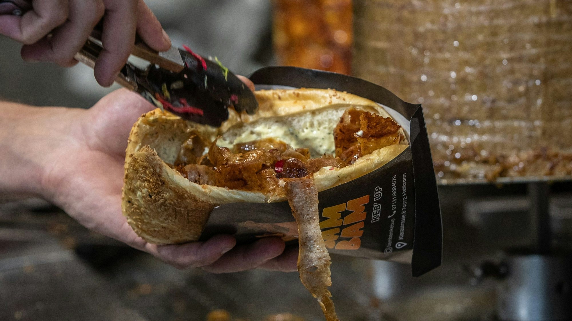 PRODUKTION - 07.08.2024, Baden-Württemberg, Heilbronn: Ein Mitarbeiter einer Dönerbude legt Fleisch in einen Döner. (zu dpa: «Obergrenze für Dönerbuden? Das steckt hinter der CDU-Idee») Foto: Christoph Schmidt/dpa +++ dpa-Bildfunk +++