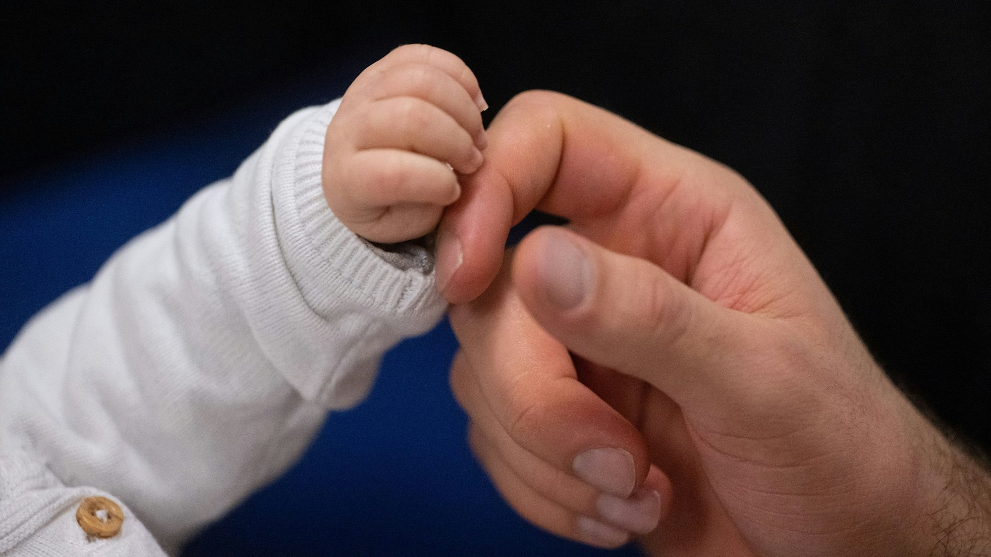 Ein Vater berührt die Hand seines Kindes. (Symbolbild)