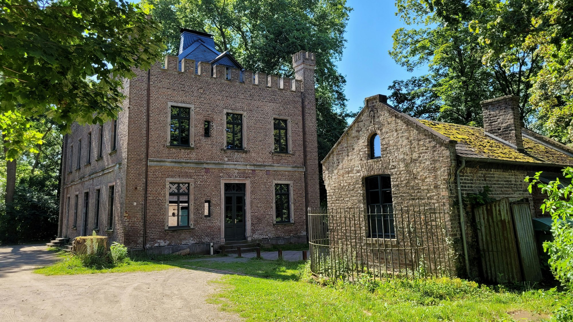 Ein historisches Herrenhaus, daneben ein deutlich kleineres Gebäude.