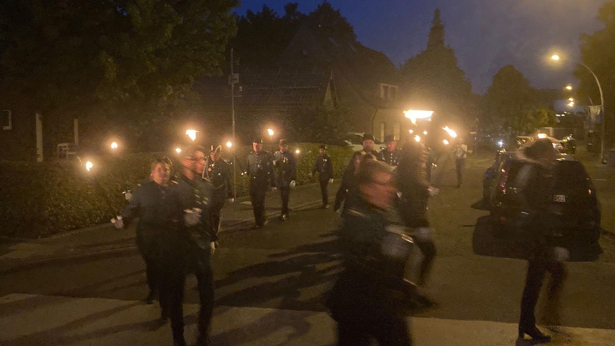 Das Bild zeigt mehrere Fackelträger in der Dunkelheit, die zum Schützenplatz ziehen.