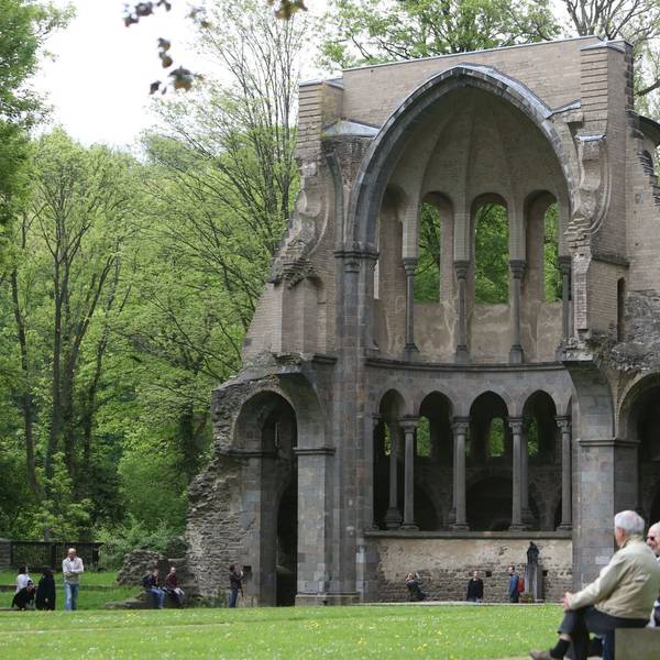 Menschen auf einer Bank vor der Chorruine des Klosters Heisterbach-