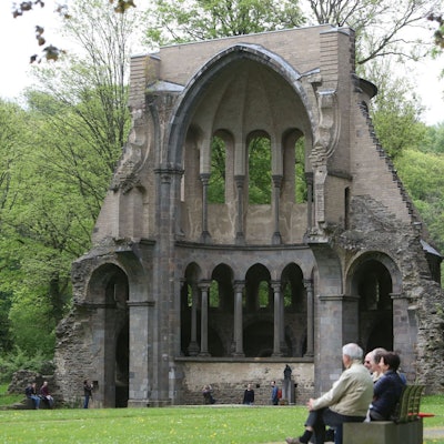 Menschen auf einer Bank vor der Chorruine des Klosters Heisterbach-