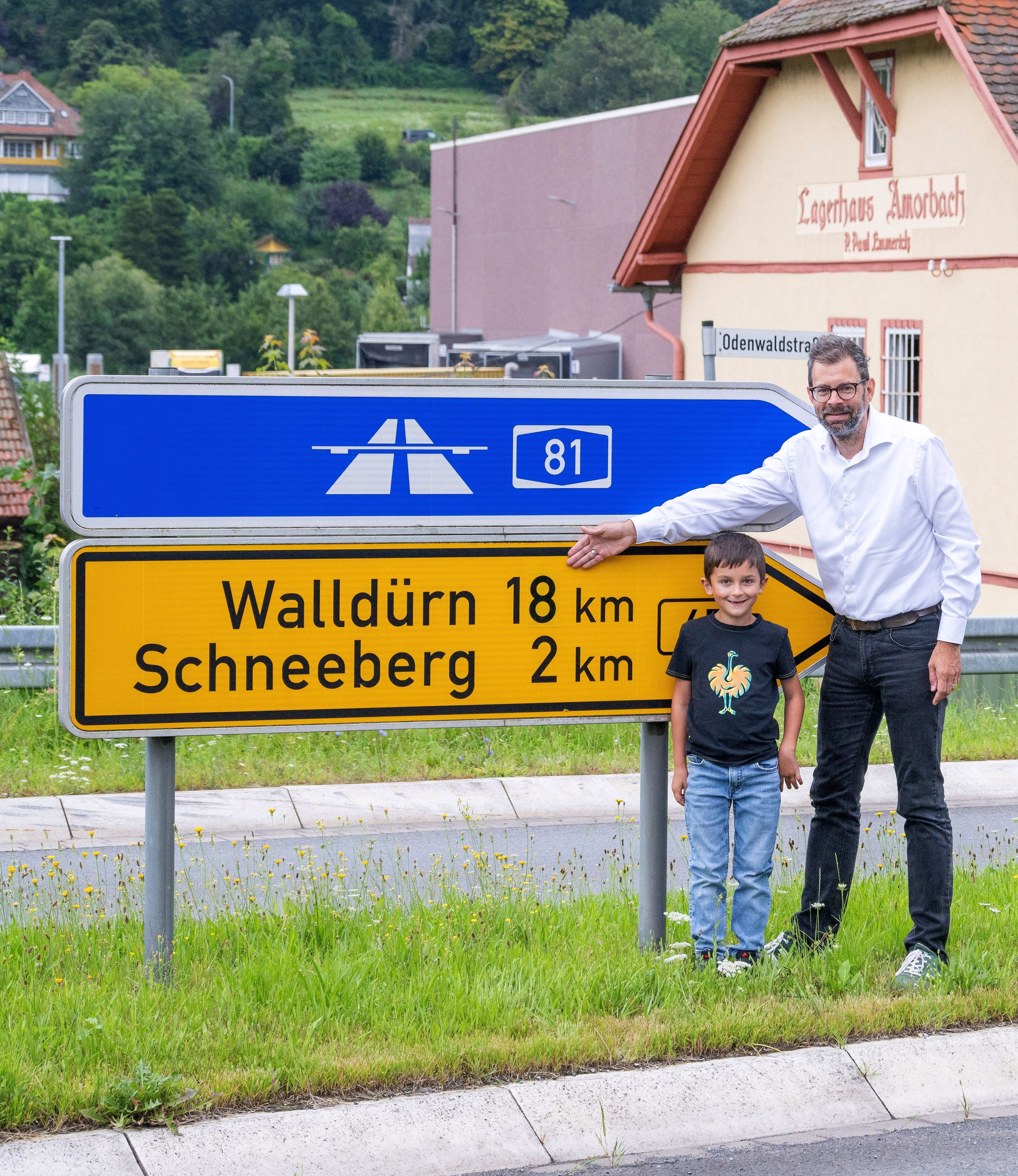 HANDOUT - 03.09.2023, Bayern, Schneeberg: Der Miltenberger Landrat Jens Marco Scherf (Bündnis 90/Die Grünen, r) steht mit dem siebenjährigen Schüler Valentin Weiss an einem Verkehrshinweisschild.