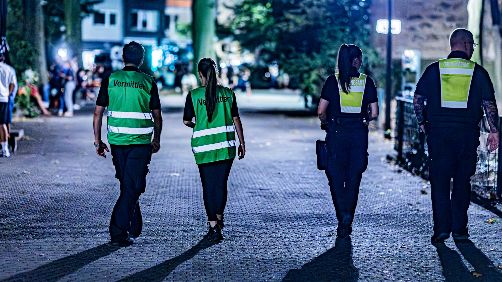 Zwei Frauen und zwei Männer mit Warnwesten gehen über den Brüsseler Platz.