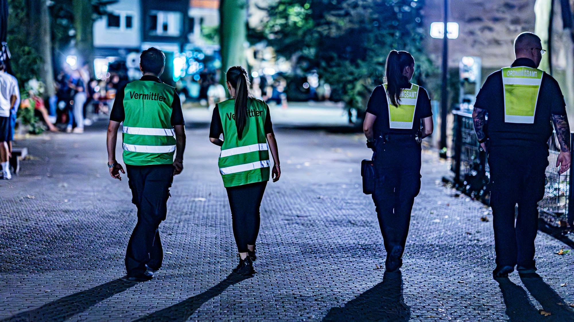 Zwei Frauen und zwei Männer mit Warnwesten gehen über den Brüsseler Platz.