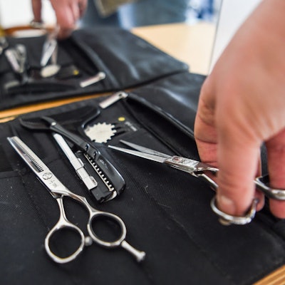 Eine Friseurin nimmt eine Haarschere aus ihrer Tasche. (Archivbild)