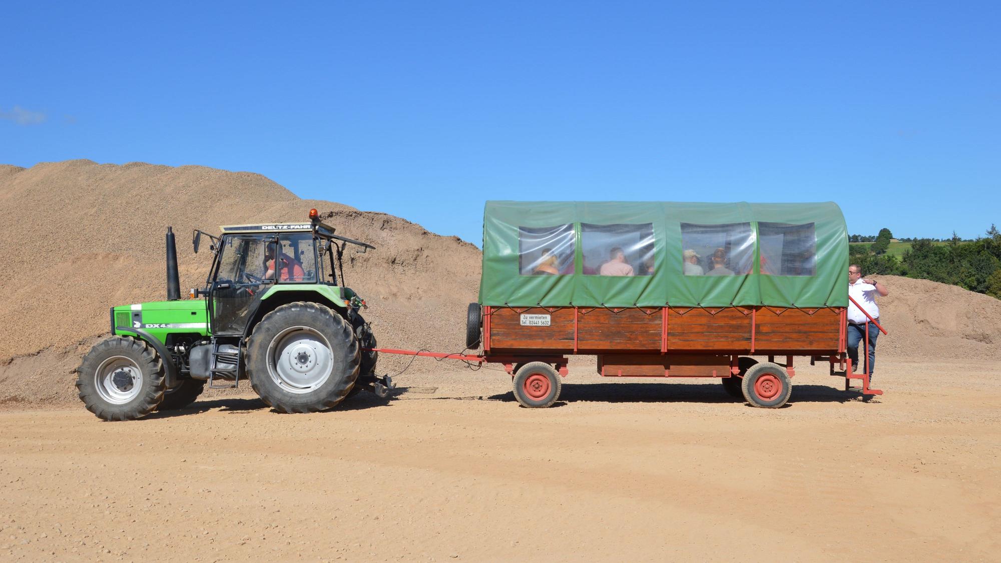 Ein Planwagen wird von einem Traktor gezogen.