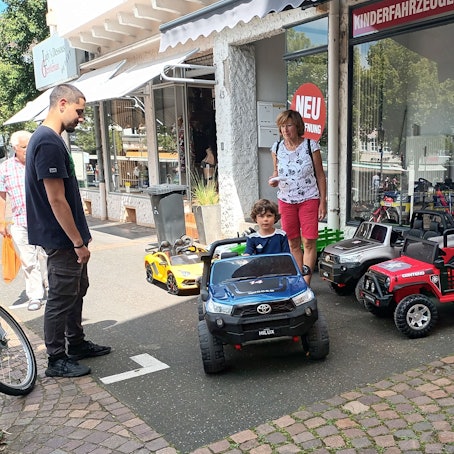 Zwei Erwachsene und ein Kind in einem Miniauto auf dem Siegburger Markt