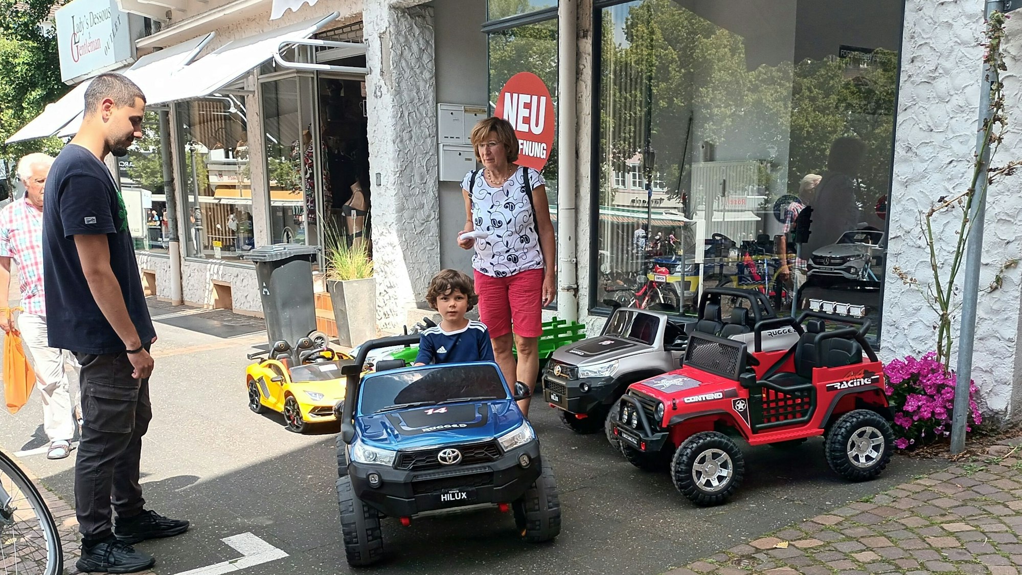 Zwei Erwachsene und ein Kind in einem Miniauto auf dem Siegburger Markt