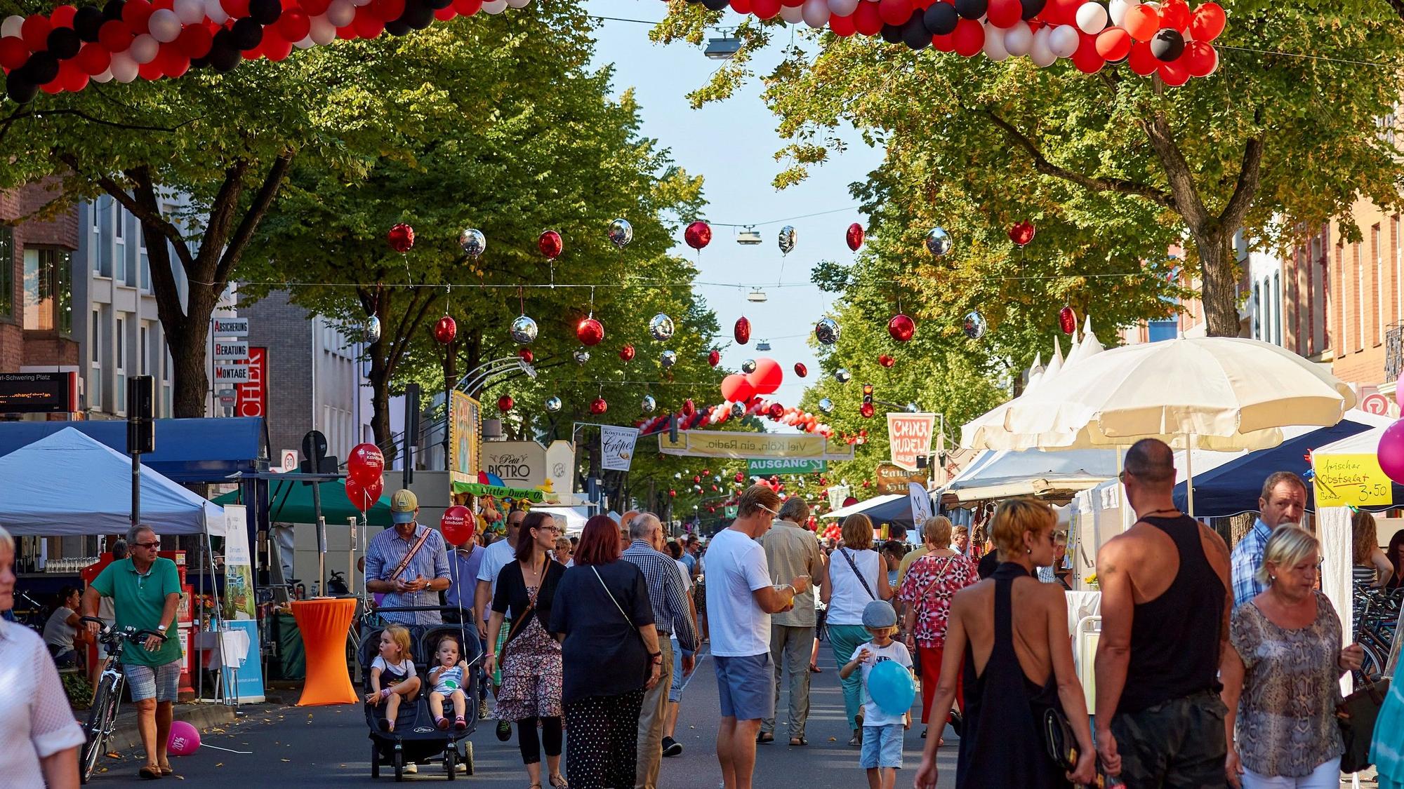 Menschen laufen über eine sommerliche und geschmückte Einkaufsstraße.