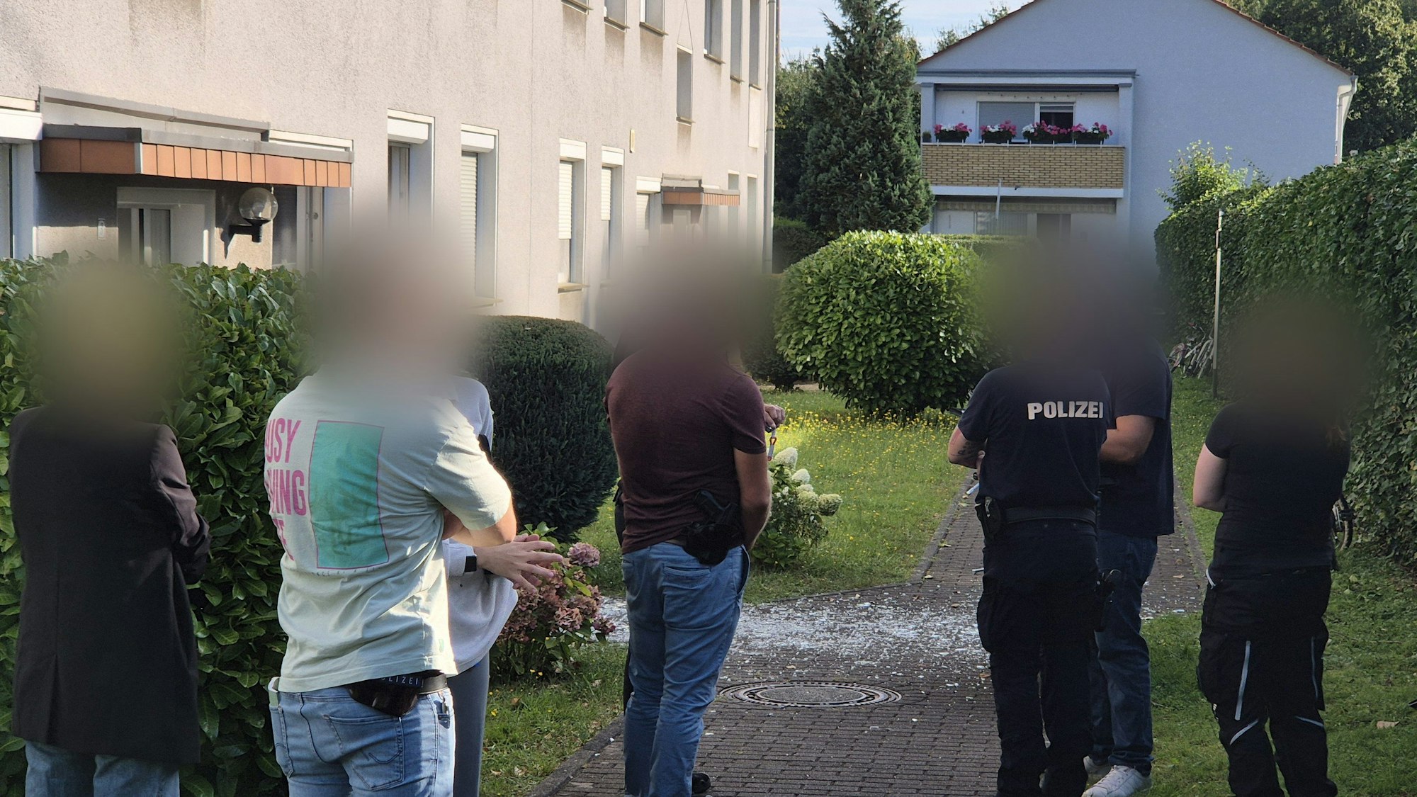 12.08.2024, Nordrhein-Westfalen, Köln: Einsatzkräfte stehen nach einer Explosion an einem Mehrfamilienhaus im Stadtteil Zündorf.