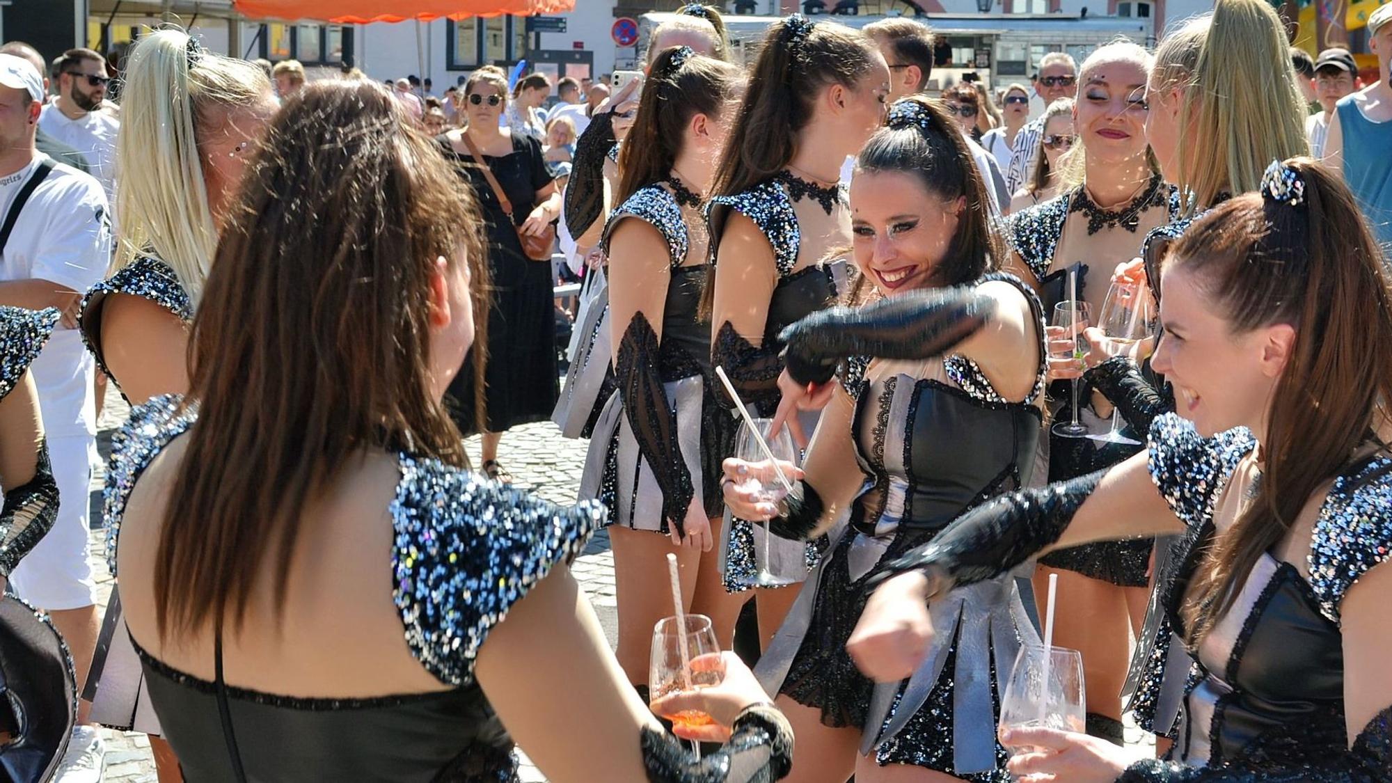 Cheerleader oder Tänzerinnen im gleichen Kostüm stehen im Publikum und trinken Aperol Spritz.