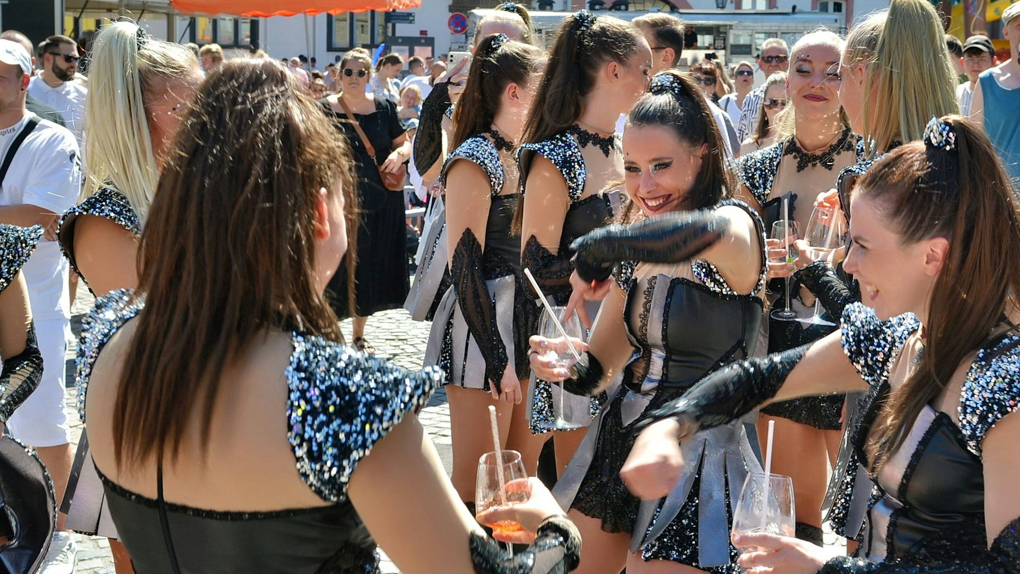 Cheerleader oder Tänzerinnen im gleichen Kostüm stehen im Publikum und trinken Aperol Spritz.