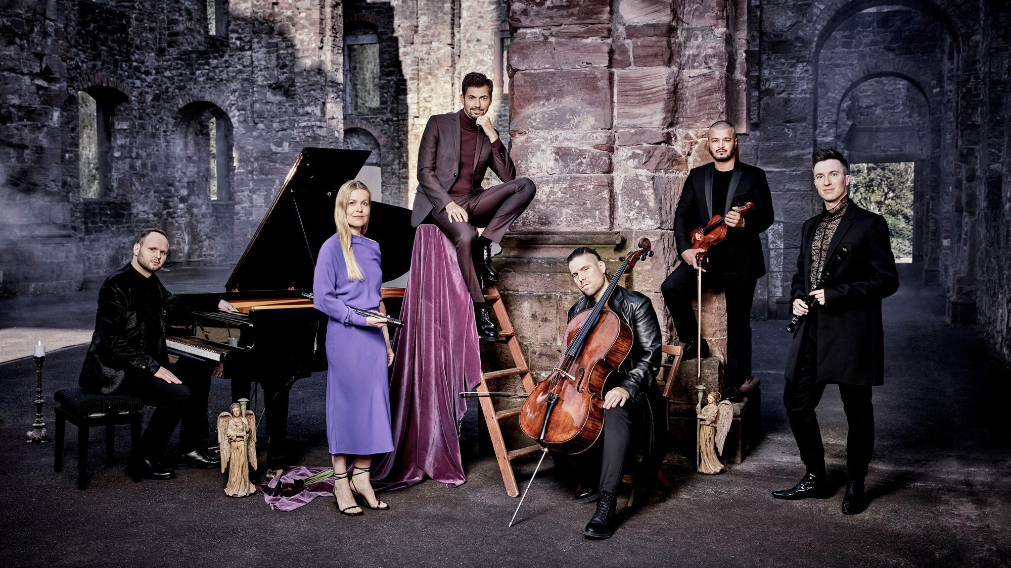 Auf dem Bild sind der Sänger Valer Sabado und die Band Spark zu sehen, die mit ihren Instrumenten posieren. Sie sind in einer Burgruine.
