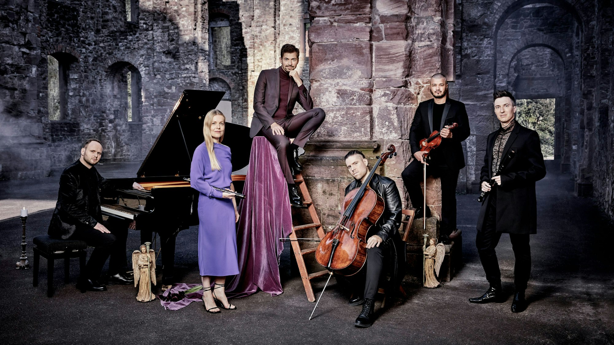 Auf dem Bild sind der Sänger Valer Sabado und die Band Spark zu sehen, die mit ihren Instrumenten posieren. Sie sind in einer Burgruine.