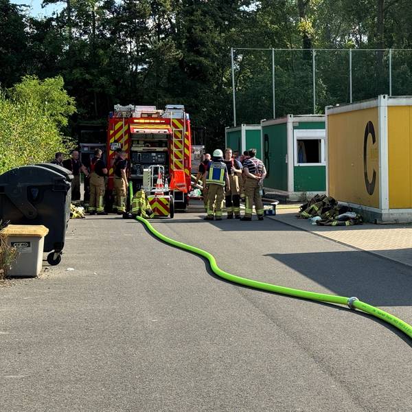 Das Bild zeigt Feuerwehrleute im Einsatz an einem Containerdorf.