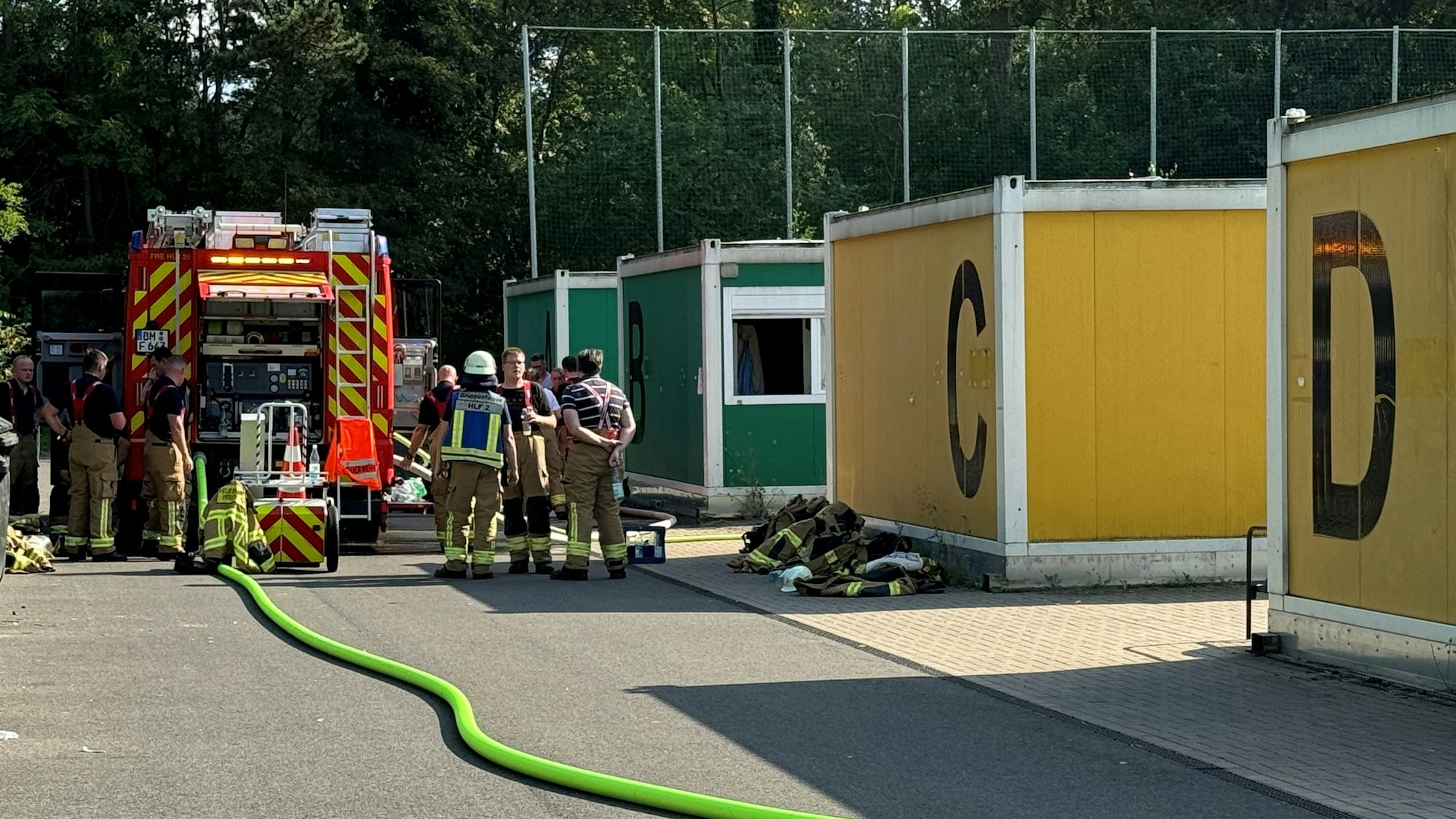 Das Bild zeigt Feuerwehrleute im Einsatz an einem Containerdorf.